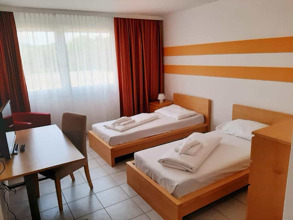 Twin bedroom with wooden beds, desk, and orange striped accent wall in Vienna room