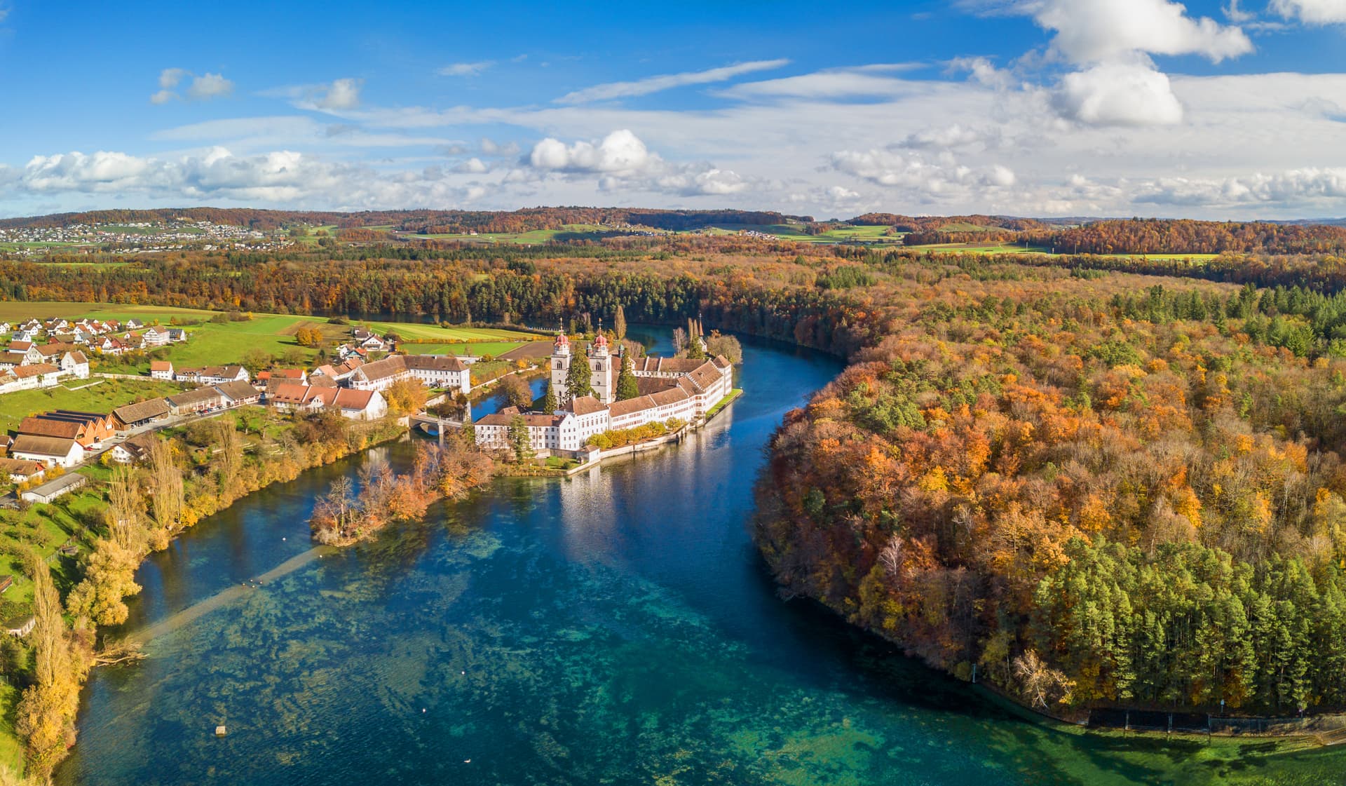 Monastery complex on river island with autumn foliage and village, Rheinau.