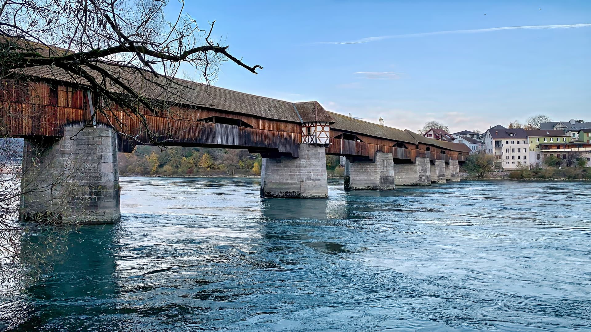 Covered wooden bridge on stone piers crossing a wide river near Bad Säckingen town.