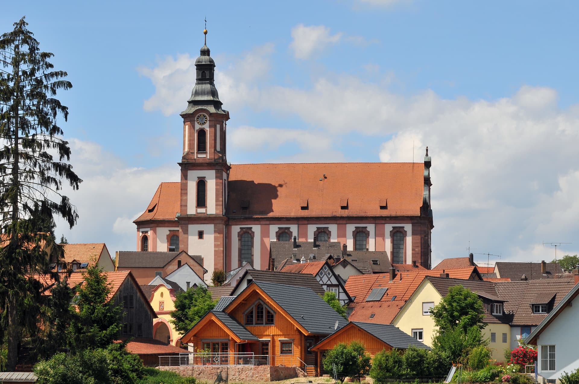 Baroque church tower rising above terracotta roofs in Ettenheim town center.