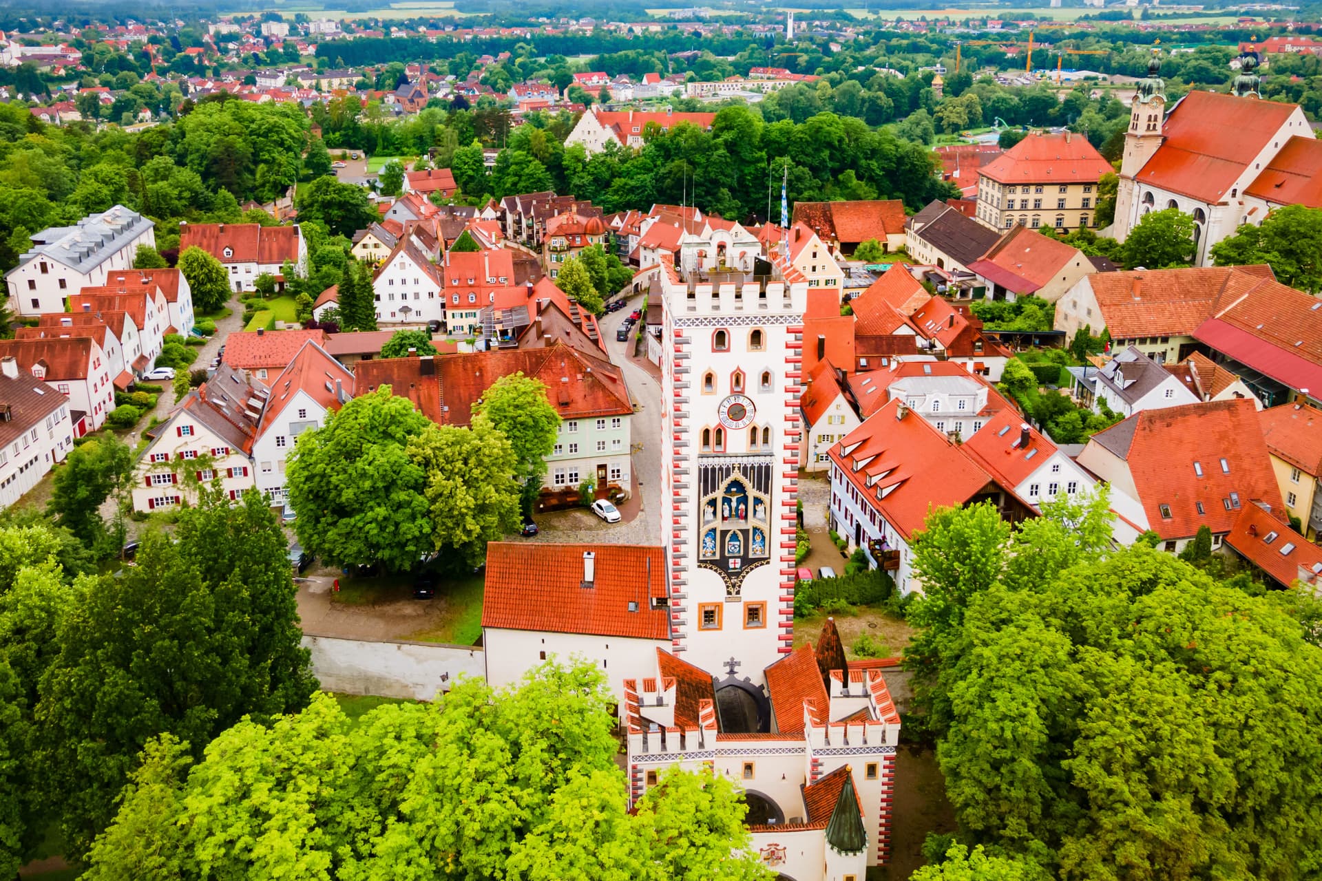 Aerial view of Landsberg town center with historic tower, red roofs, and lush green trees.