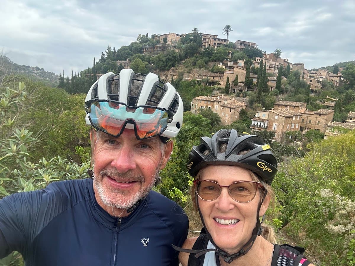 Cyclists wearing helmets taking selfie with historic stone village in background