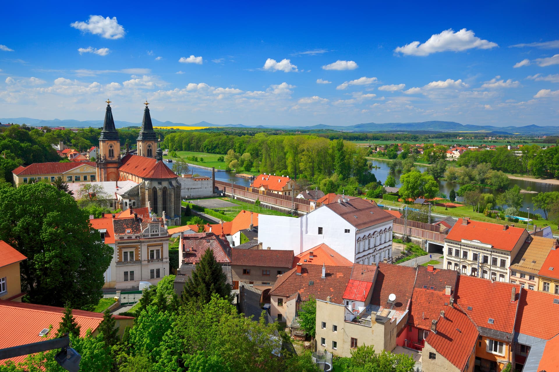Roudnice nad Labem town view with church spires, red roofs, and river in spring.