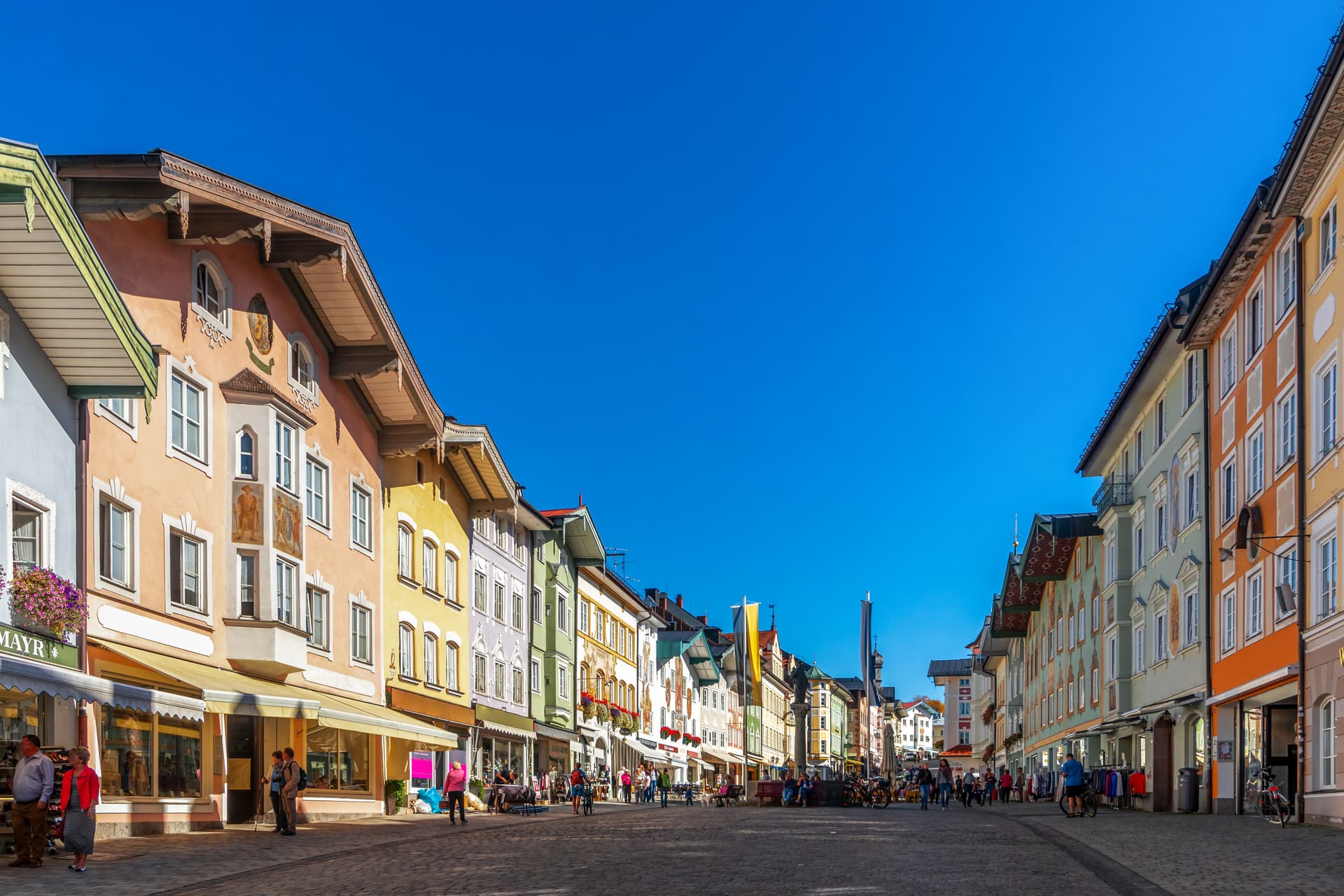 Cobblestone pedestrian street lined with colorful historic buildings under bright blue sky in Bad Tölz.