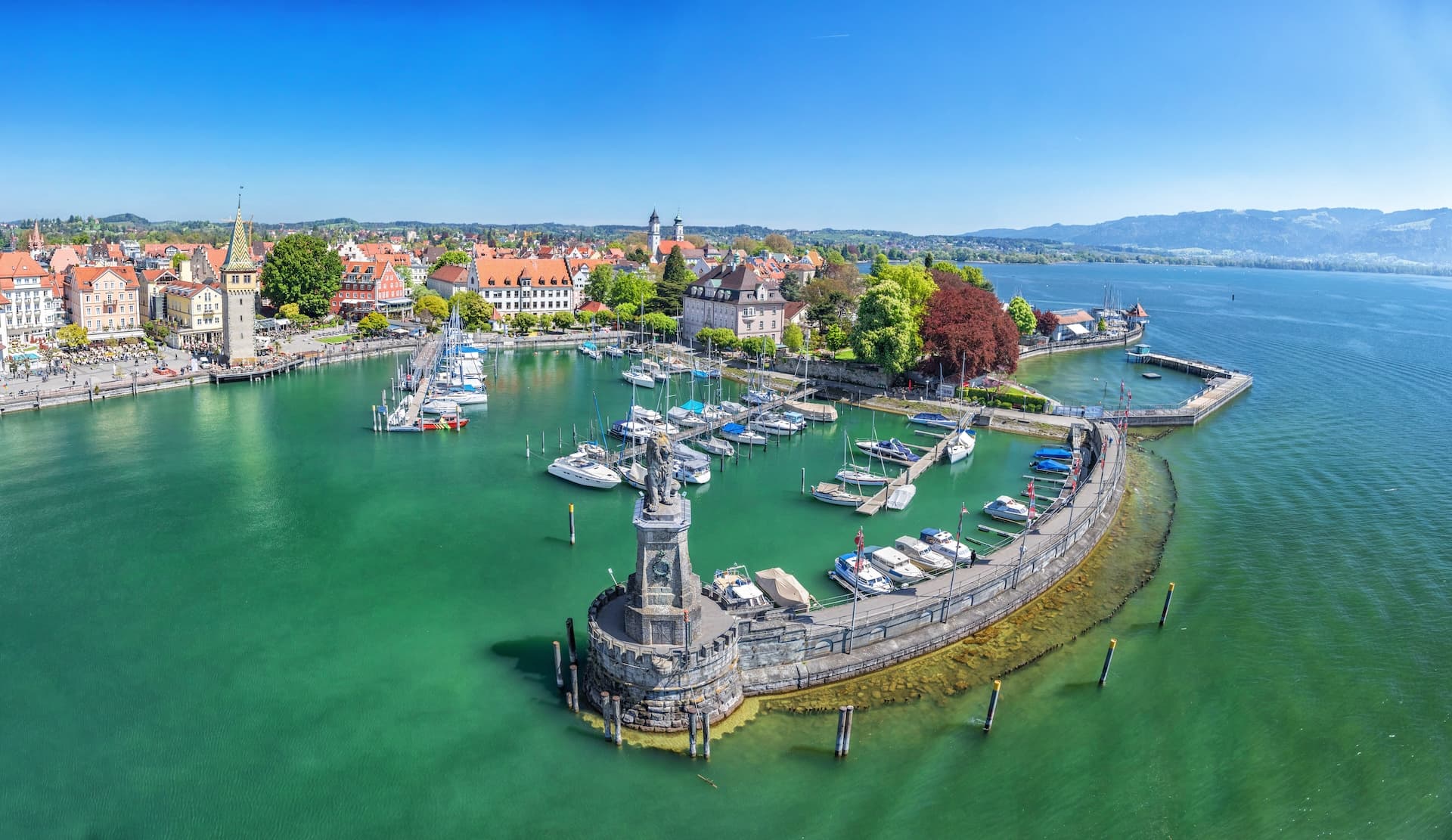 Harbor on Lake Constance with lion statue entrance, Lindau, Bavaria, Germany, and distant mountains.